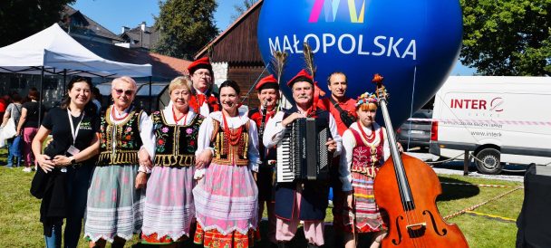 roześmiany zespół folklorystyczny pozujący do zdjęcia. po prawej stronie kobieta z kontrabasem, obok niej mężczyzna z akordeonem.