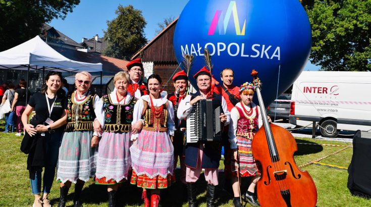roześmiany zespół folklorystyczny pozujący do zdjęcia. po prawej stronie kobieta z kontrabasem, obok niej mężczyzna z akordeonem.