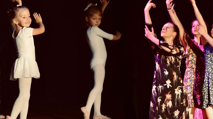 Kolaż zdjęć. Z lewej strony dwie małe baletnice w białym body, roześmiane. Z prawej strony tancerki w kolorowych sukienkach, dłonie i ręce uniesione w górę. Czarne tło.